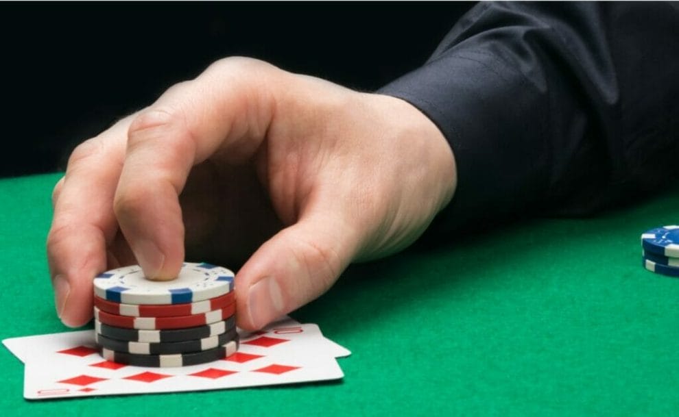 A player places some poker chips on top of his cards.