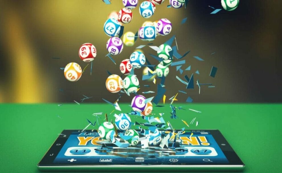 A tablet device on a green surface with bingo balls and confetti above.