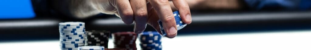 A player puts more chips down on a poker table.