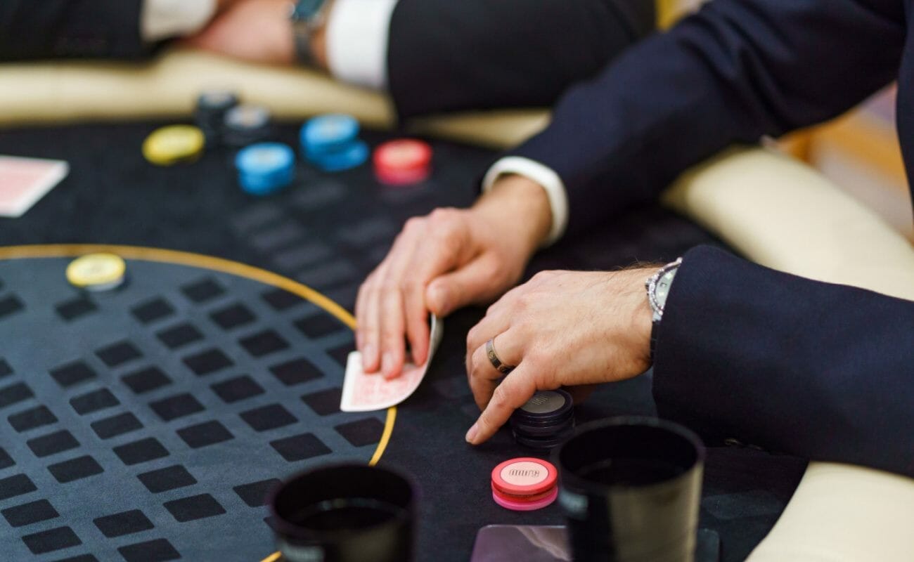 A man in a suit holding playing cards and poker chips.