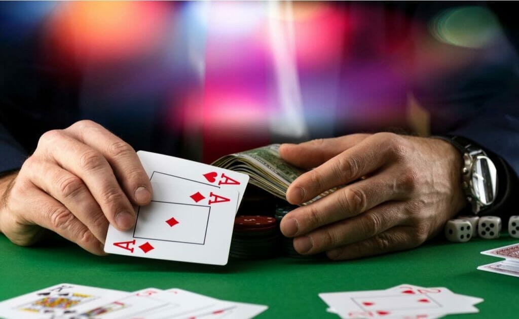 A player holding two aces and a stack of cash.