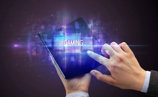 A man’s hand touches the screen of a foldable phone with the word ‘gaming’ displayed on the screen.
