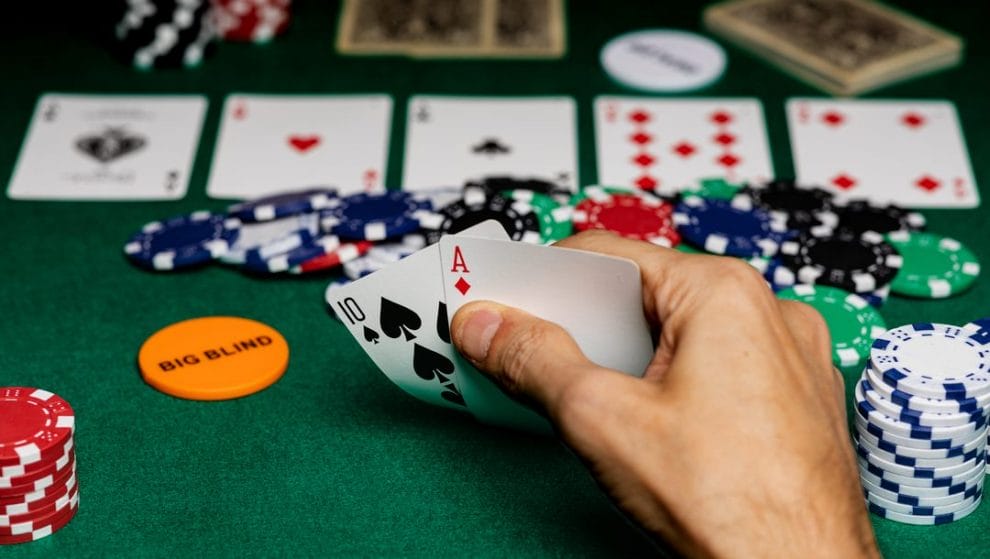 A poker player with the big blind button checks his hole cards.