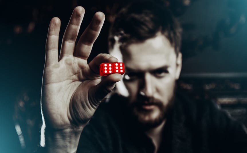 A man holding two dice up with sixes on them.