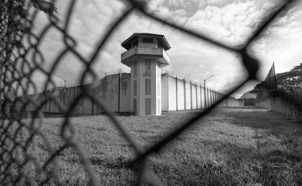 A prison guard tower behind a fence.