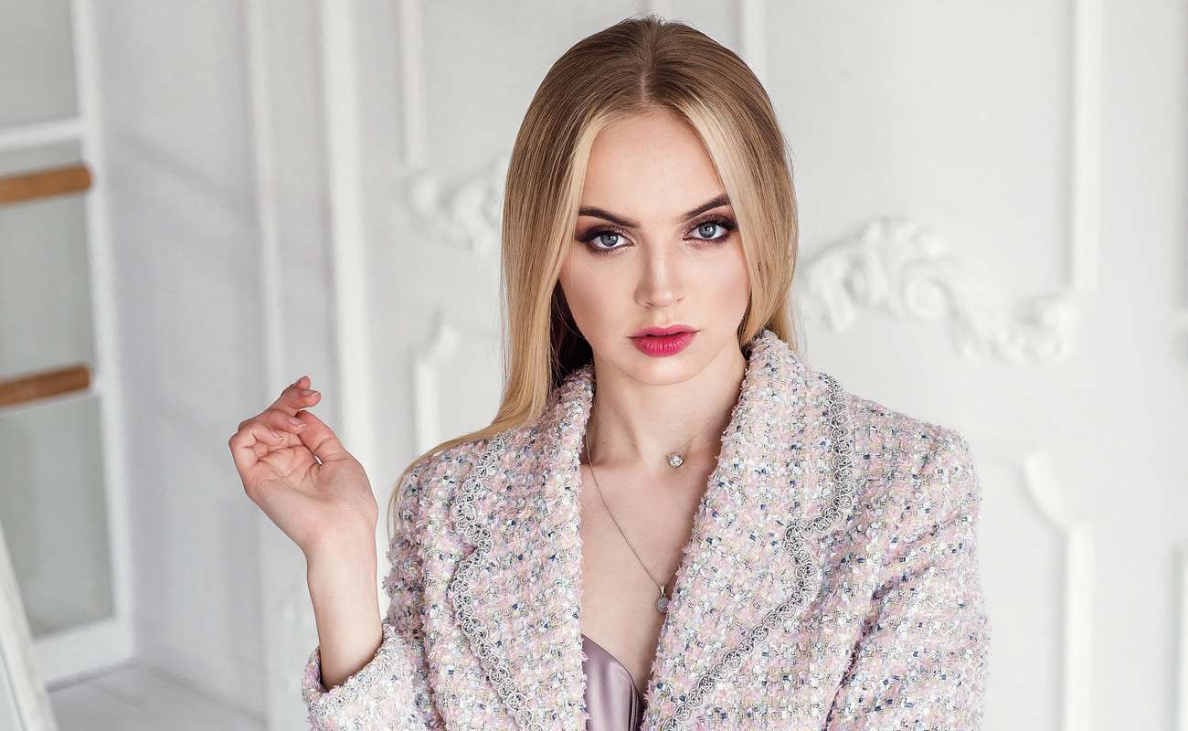  A stylishly dressed blond woman wearing a tweed jacket.