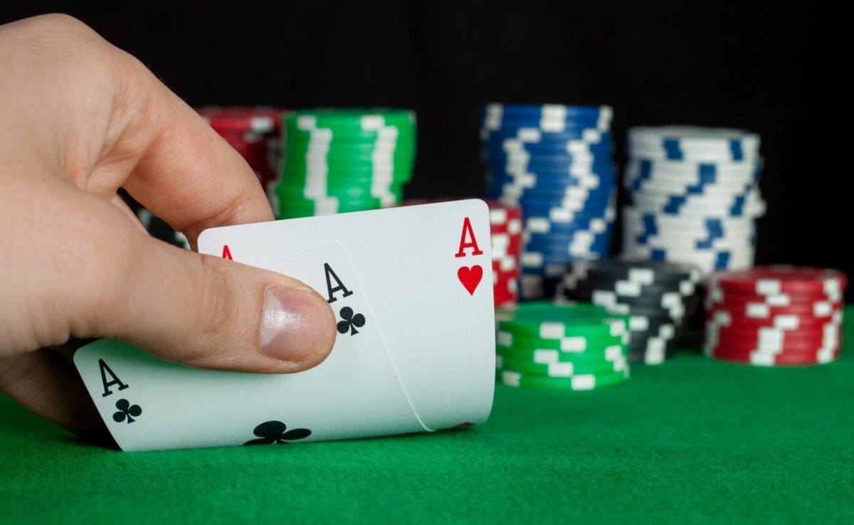 A poker player checks his hole cards and sees two aces.