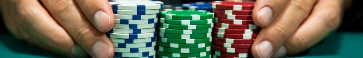 A poker player places a large bet with stacks of casino chips.
