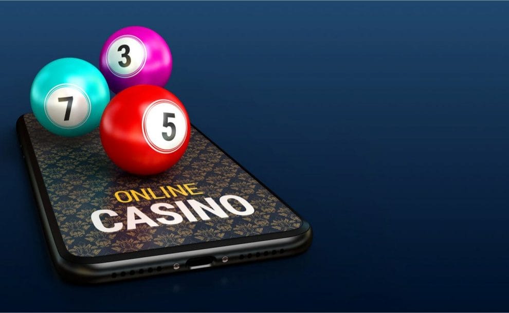 A smartphone with “online casino” written on it with bingo balls on top of the screen.