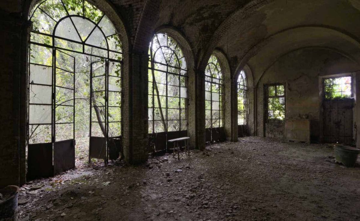 A wall of big bay windows in an abandoned building.