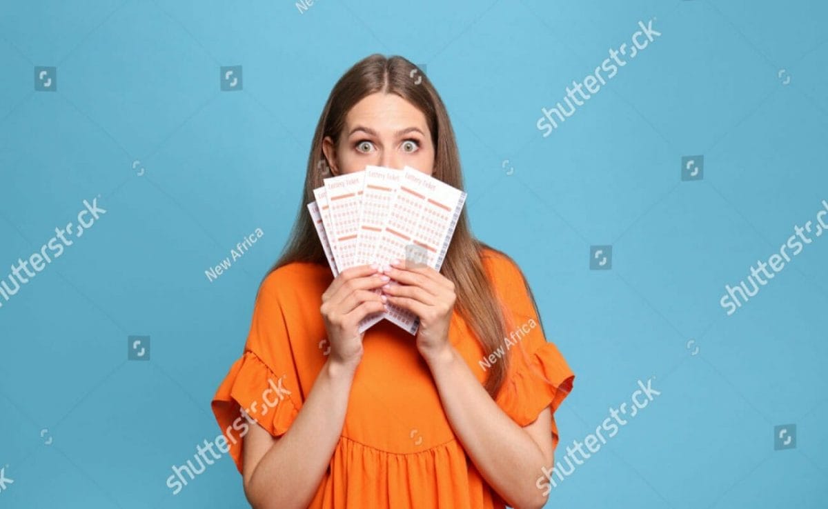 A woman in an orange blouse holds up bingo cards. 