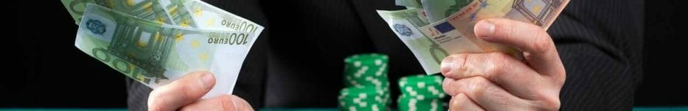 Man holding many euro notes in his hands with poker chips stacked up