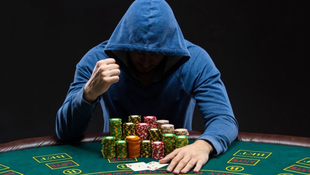 A poker player in a blue hoodie celebrates a win at the poker table.