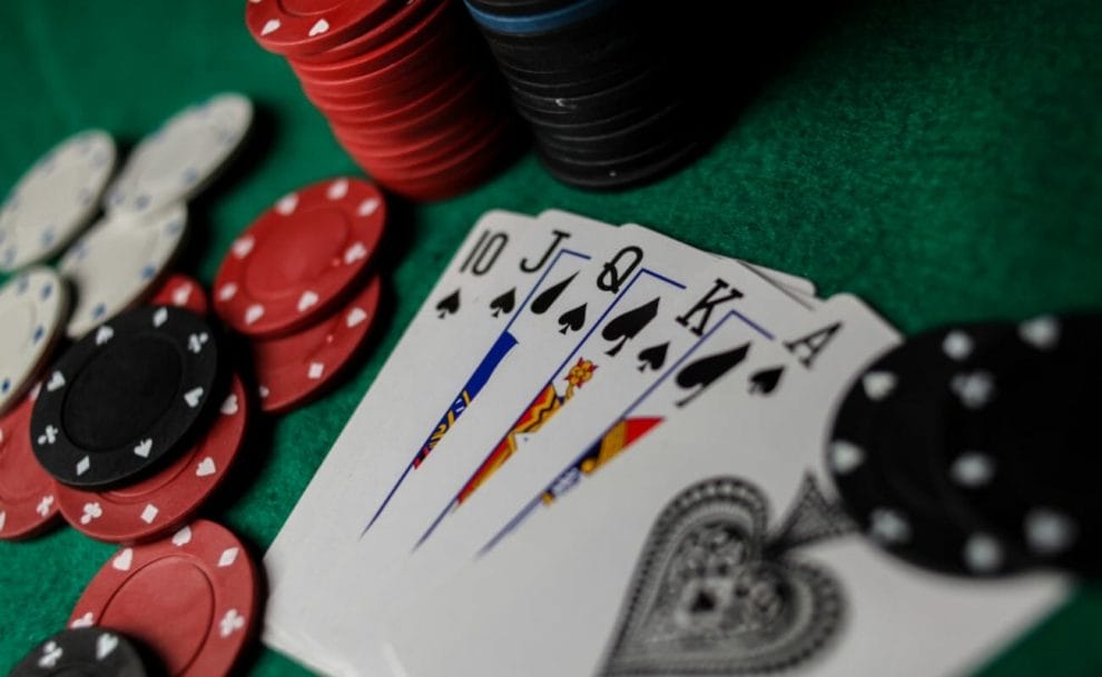 A royal flush of spades next to chips on a poker table.