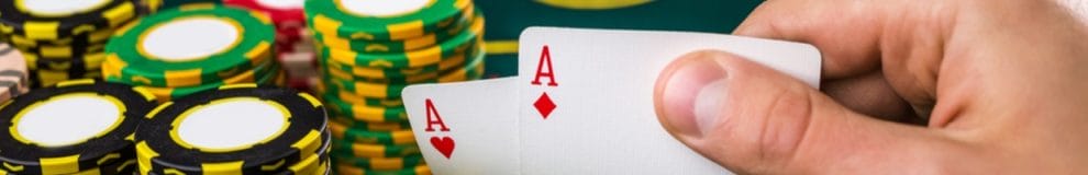 A poker player shows two ace cards.