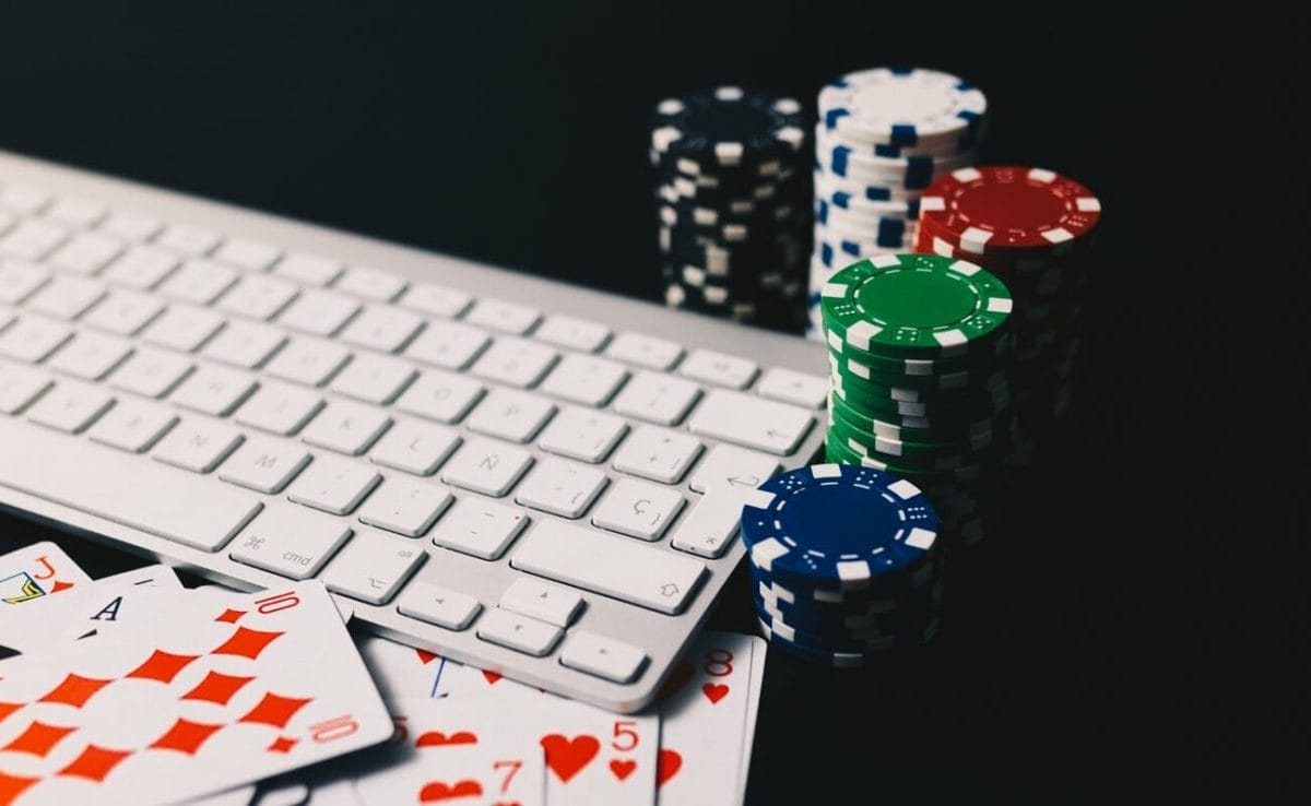 Stacks of poker chips and playing cards next to a computer keyboard.