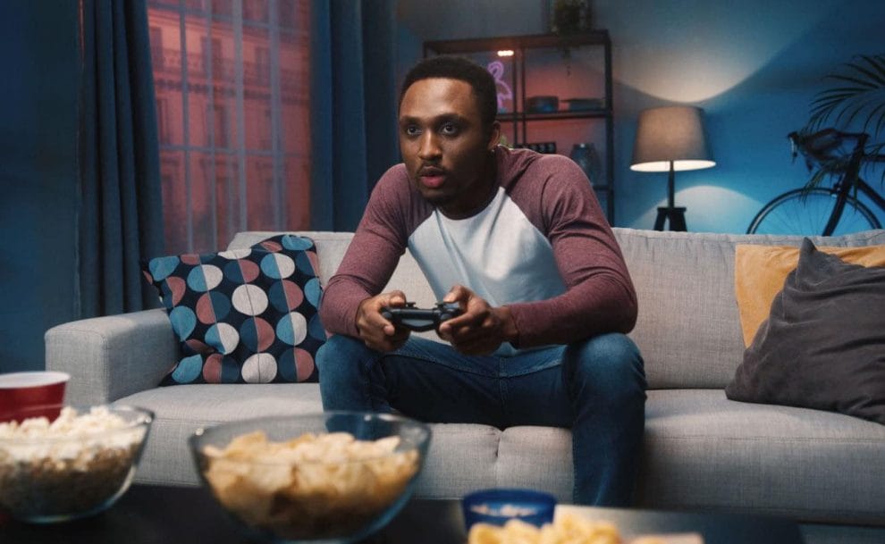 A man plays video games on his couch.