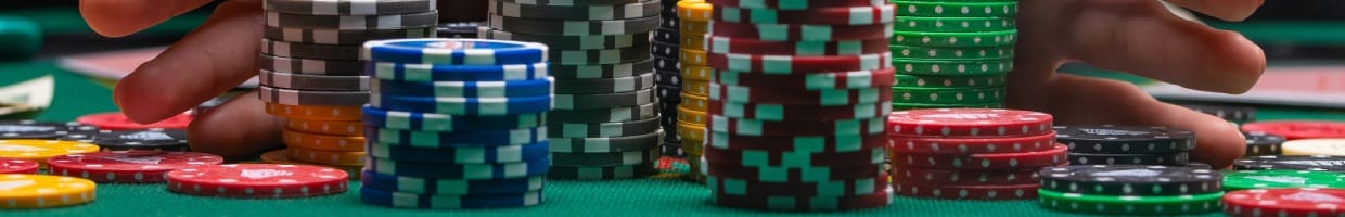 Poker chips and fingers on a green felt table.