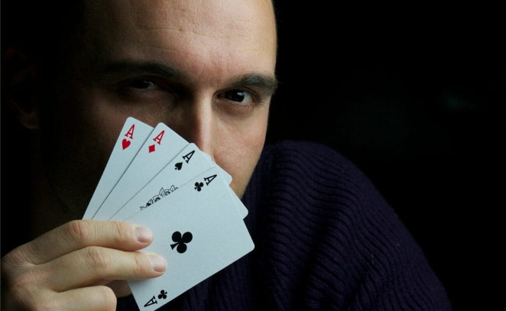 A poker player reveals four ace cards.