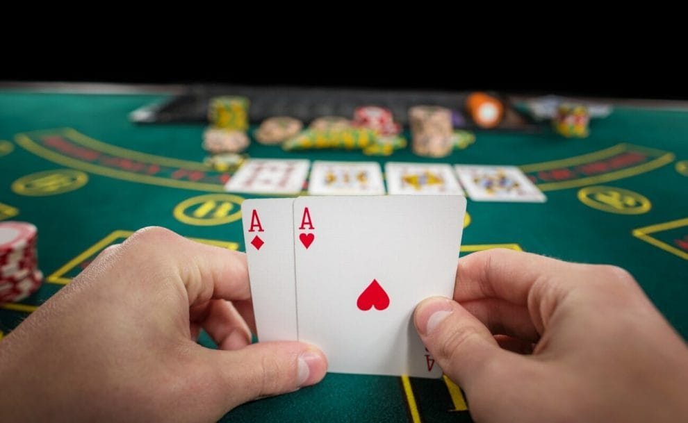 A poker player holding two ace cards at the poker table.