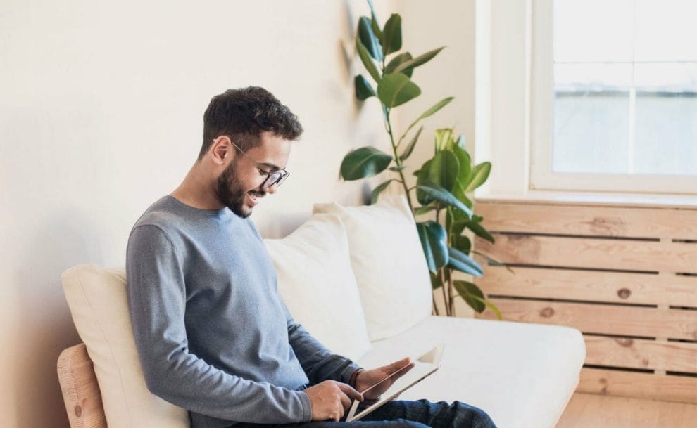 A man sitting on a couch playing on a tablet.