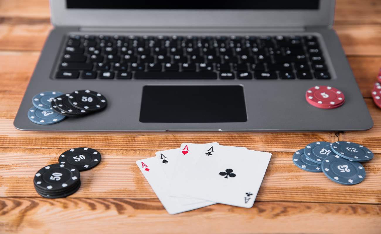 Poker cards and chips on a wooden table with a laptop.