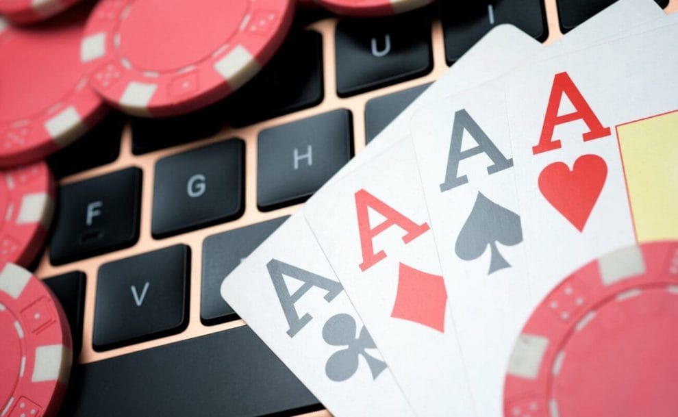 Four aces and some poker chips on a computer keyboard.