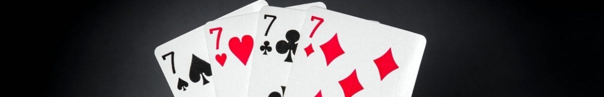 Four sevens behind stacks of casino chips.