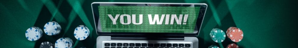 A laptop saying ‘You Win’ with poker chips next to it.