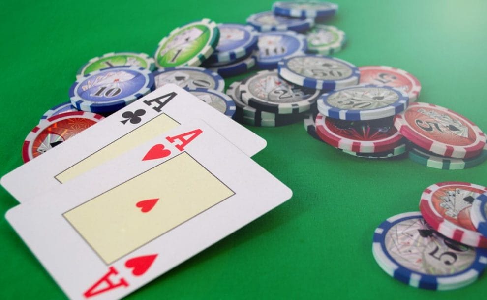 Two ace cards next to poker chips on a poker table.