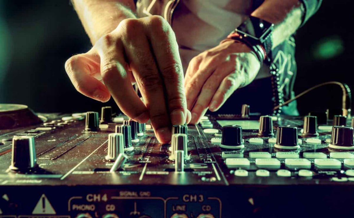 A DJ’s hand’s on his equipment.
