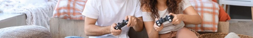 A couple playing video games on the floor of their bedroom.