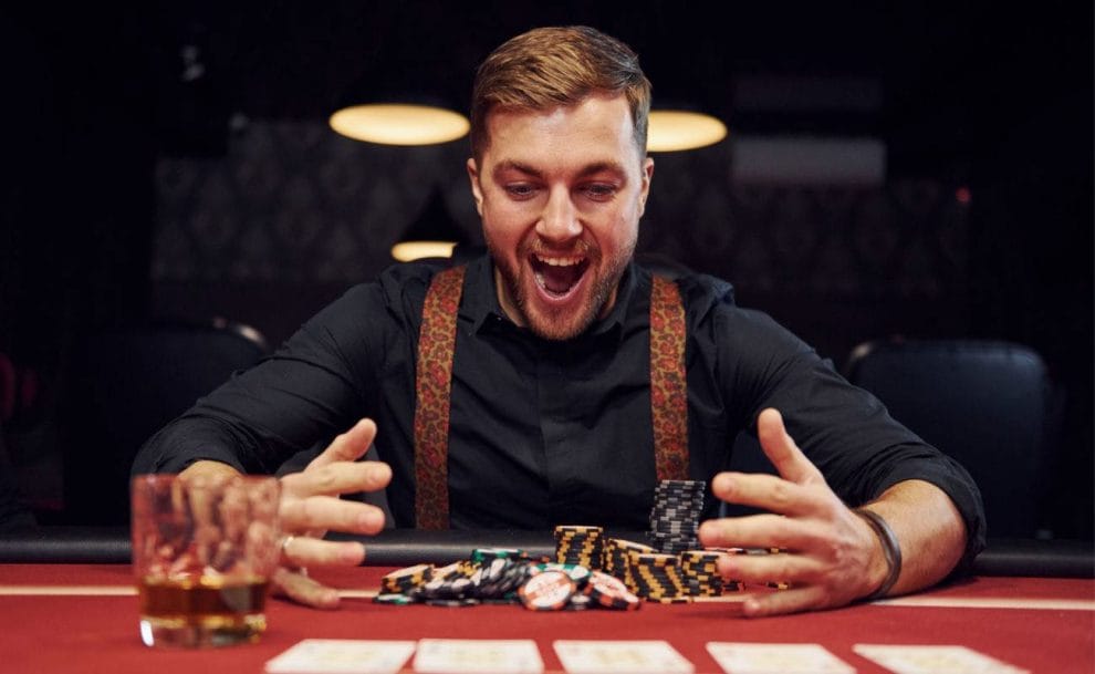 A man celebrating a win at a casino table with stacks of casino chips.