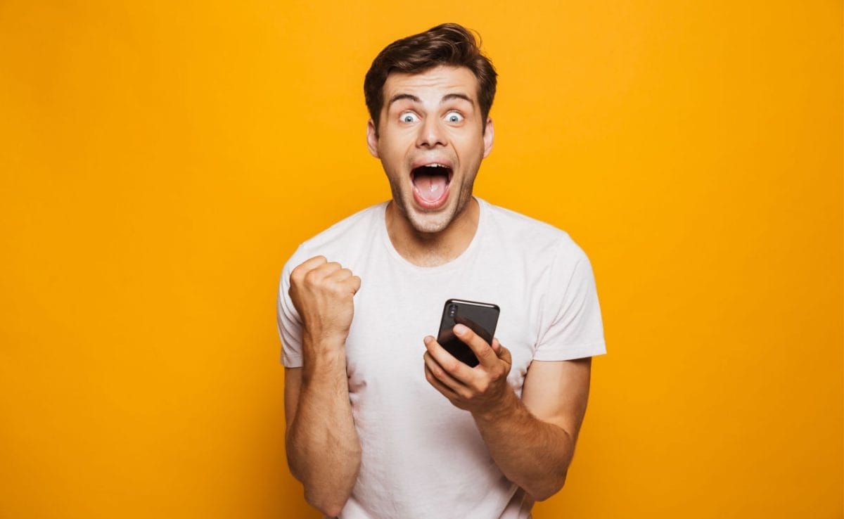A person holding a smartphone and cheering.
