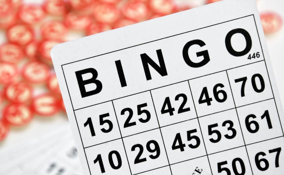 A bingo card with numbered wooden chips blurred out in the background.