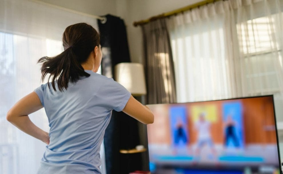 A person exercising while watching a fitness program on TV.