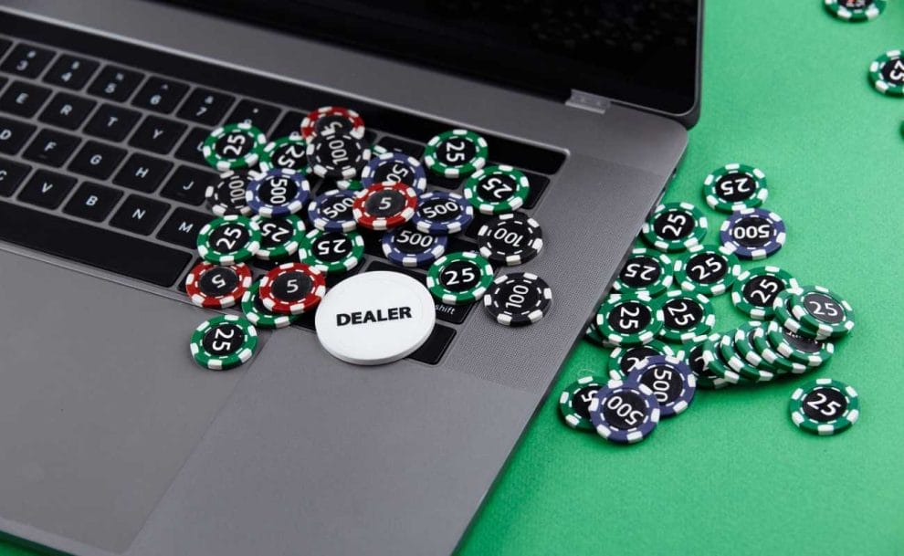 Casino chips on a gray laptop and green felt table.
