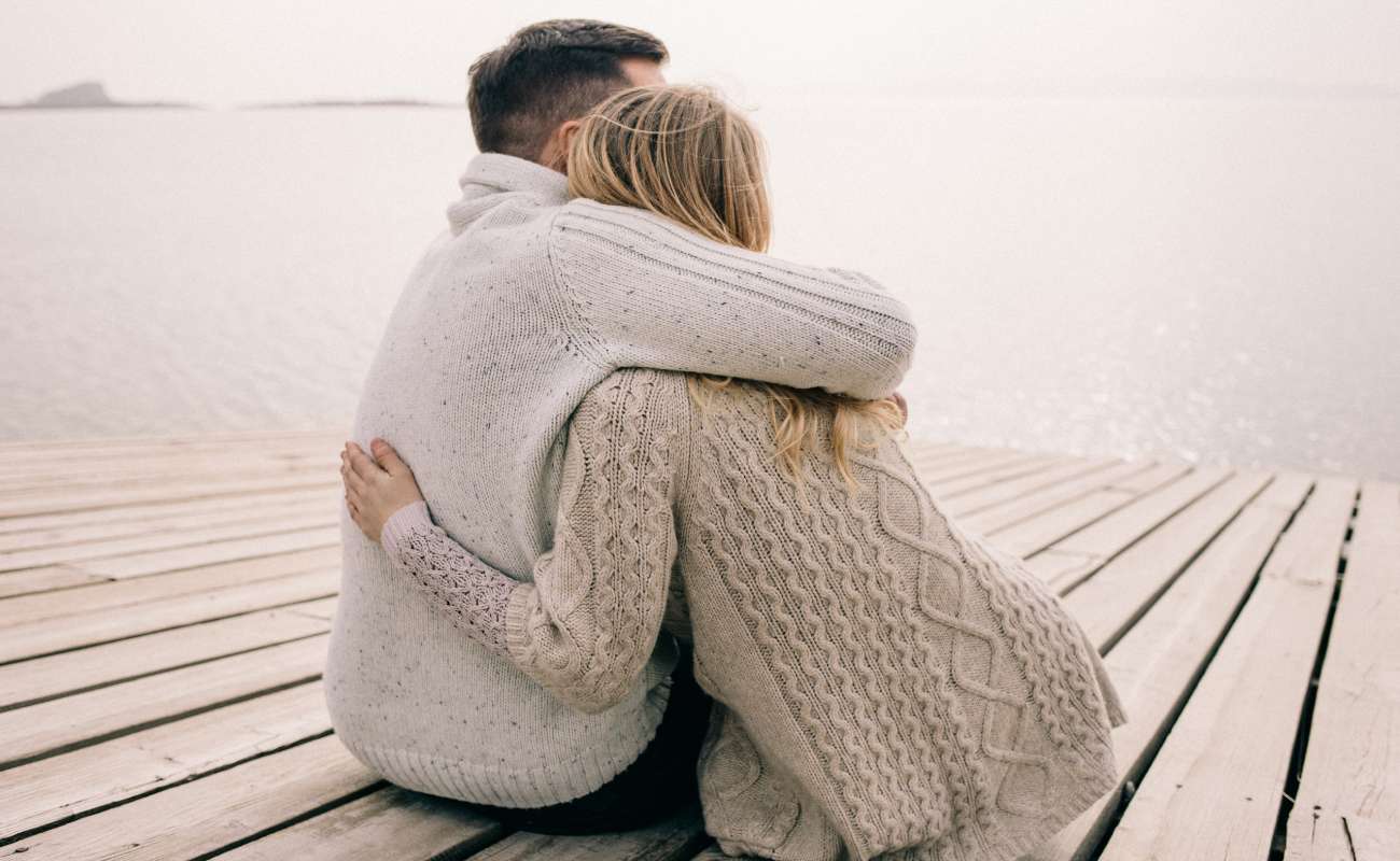 A couple hugging on a wooden deck.