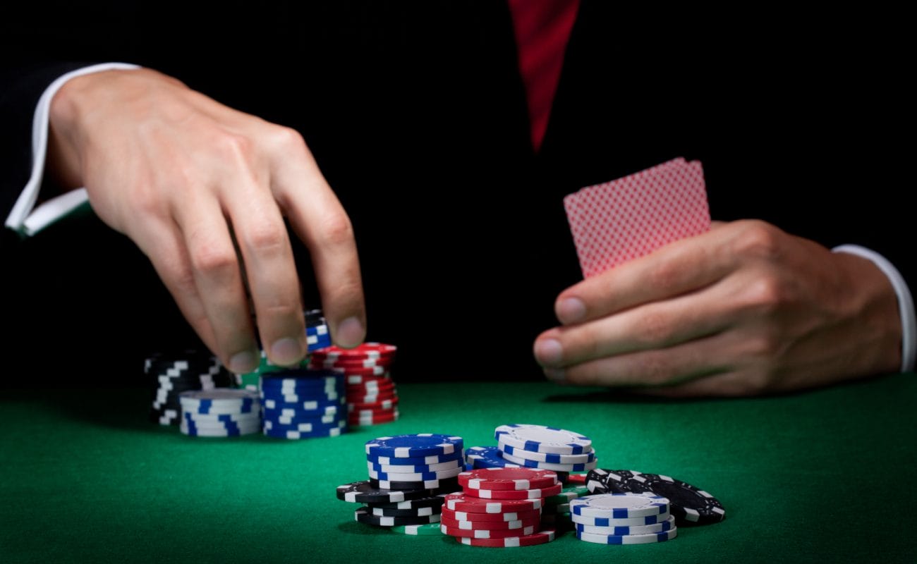 A poker player holds cards and handles chips.