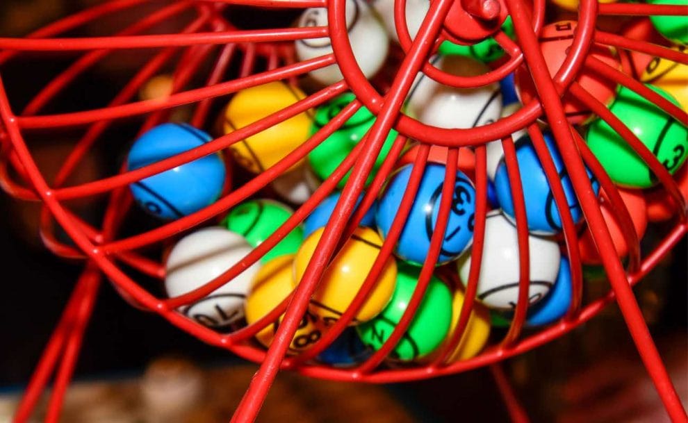 Colorful bingo balls in a red bingo cage.