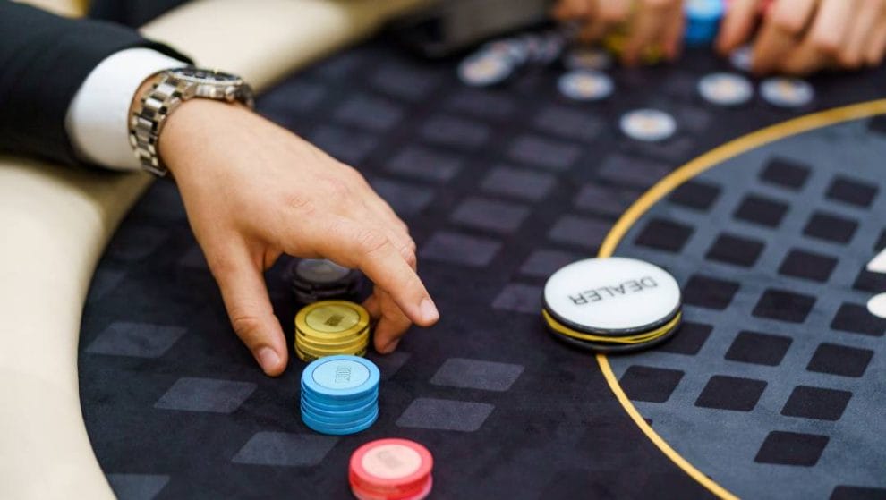 A person’s hand picking up casino chips.