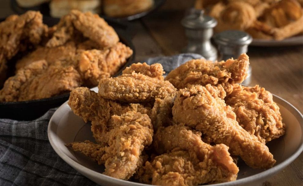 Plates of crispy fried chicken on a dining room table.