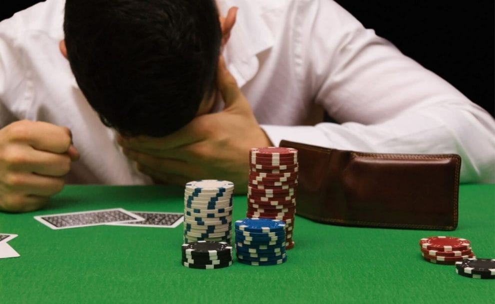 A man bowing his head in disappointment during a loss at a poker table.