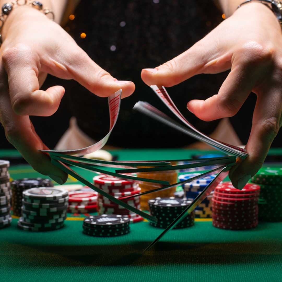 A croupier shuffling cards at a poker table.