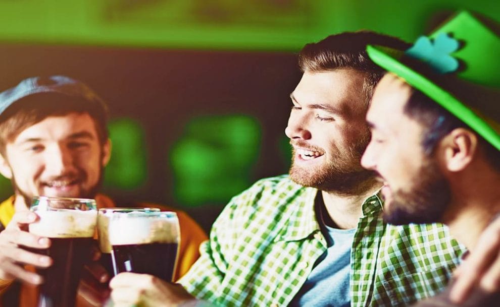 Three friends wearing green items of clothing and enjoying a Guinness.