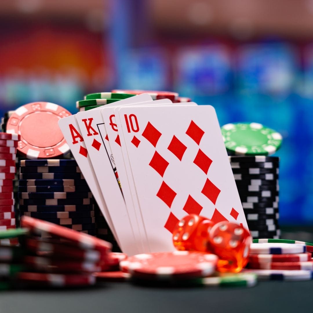 Four playing cards leaning against several stacks of casino chips.