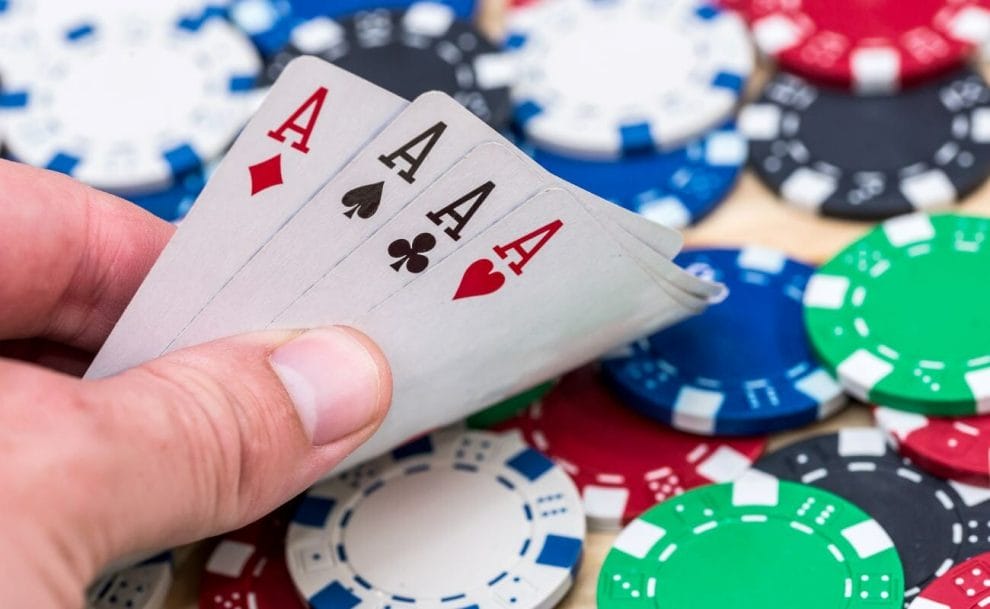 A poker player shows the four ace cards in their hand.