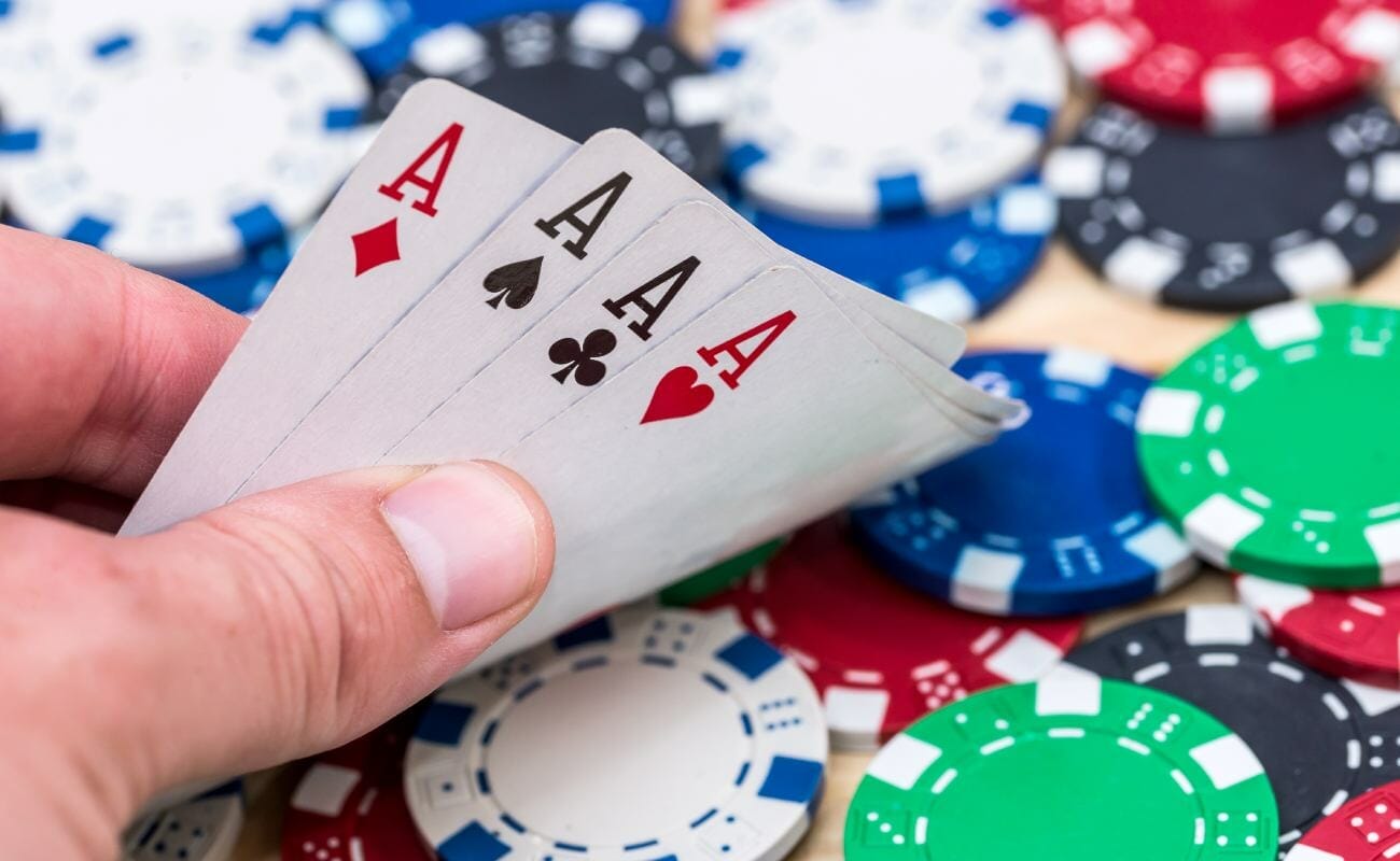 A poker player shows the four ace cards in their hand.
