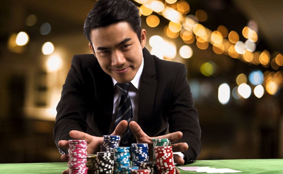 A businessman sitting at a casino table with large stacks of chips.