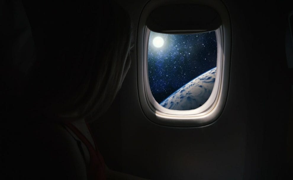 A person in a spaceship looks out toward Earth and the moon.